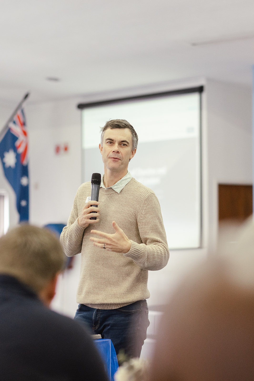 Speaker teaching on a microphone beside the presentation screen