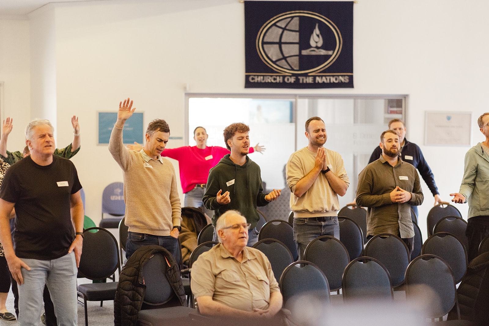Immerse gathering standing in worship with hands raised