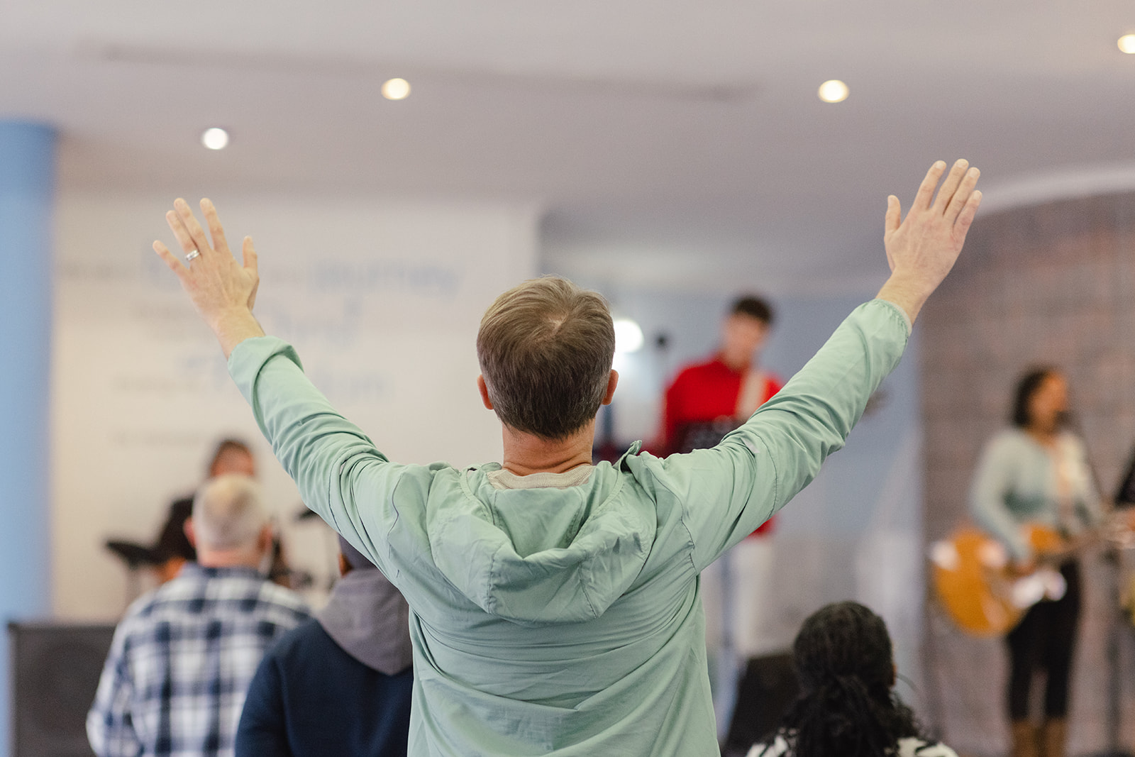 Man with both arms lifted in worship as the band plays